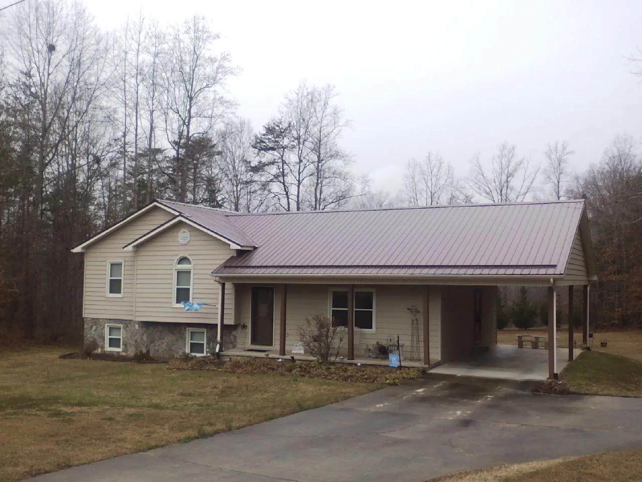 Burgundy metal roof on a tan split level home with an attached carport in Nathrop
