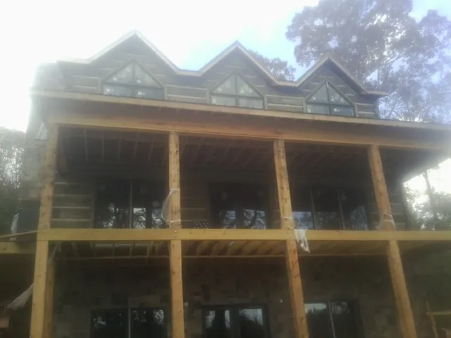 Dormers and porch framing on a large log home under construction — Roof Coating work by our crew in Nathrop