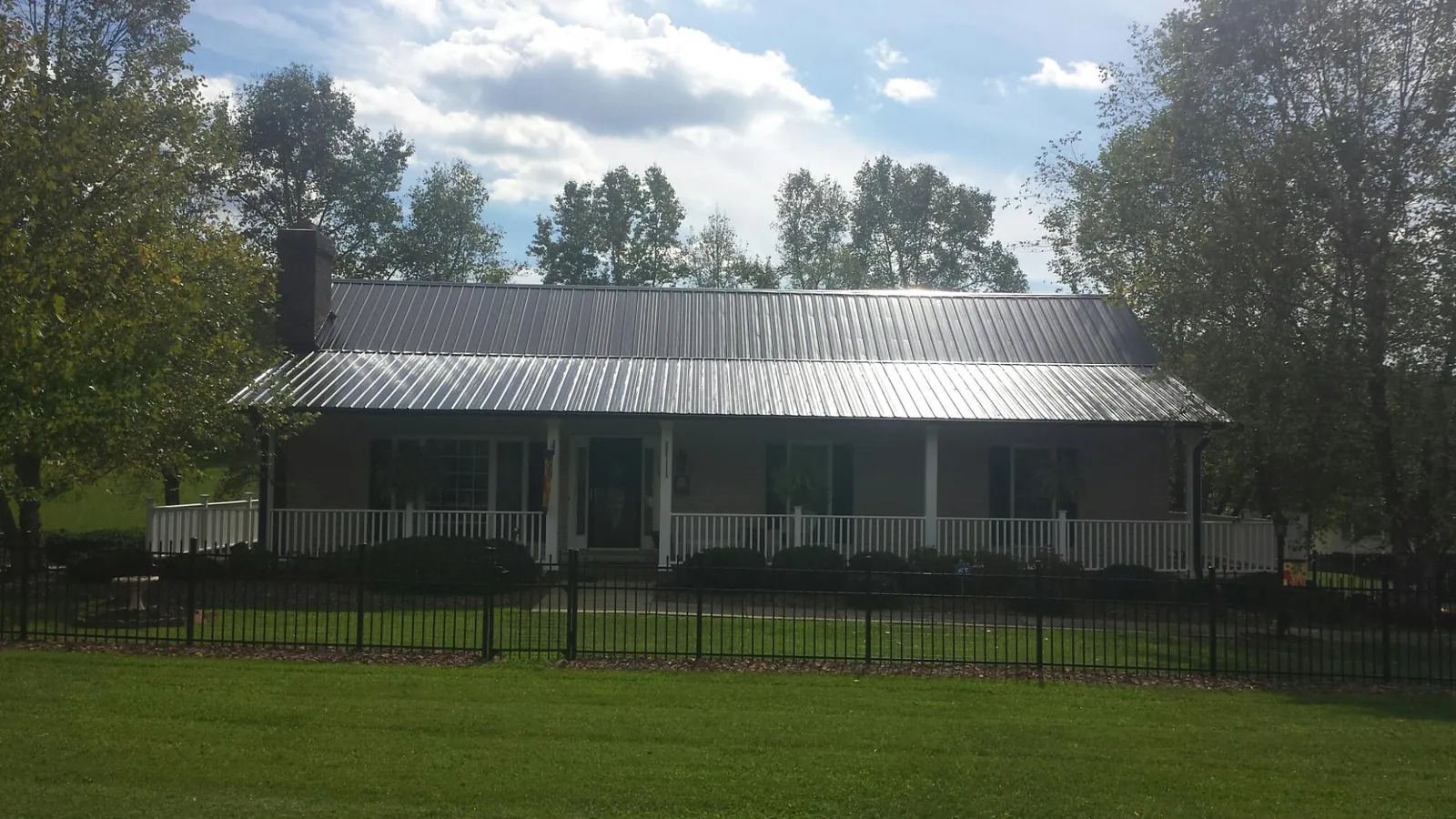 Gray metal roof on a brick ranch with a full width front porch — Gutter Guard Installation work by our crew in Nathrop