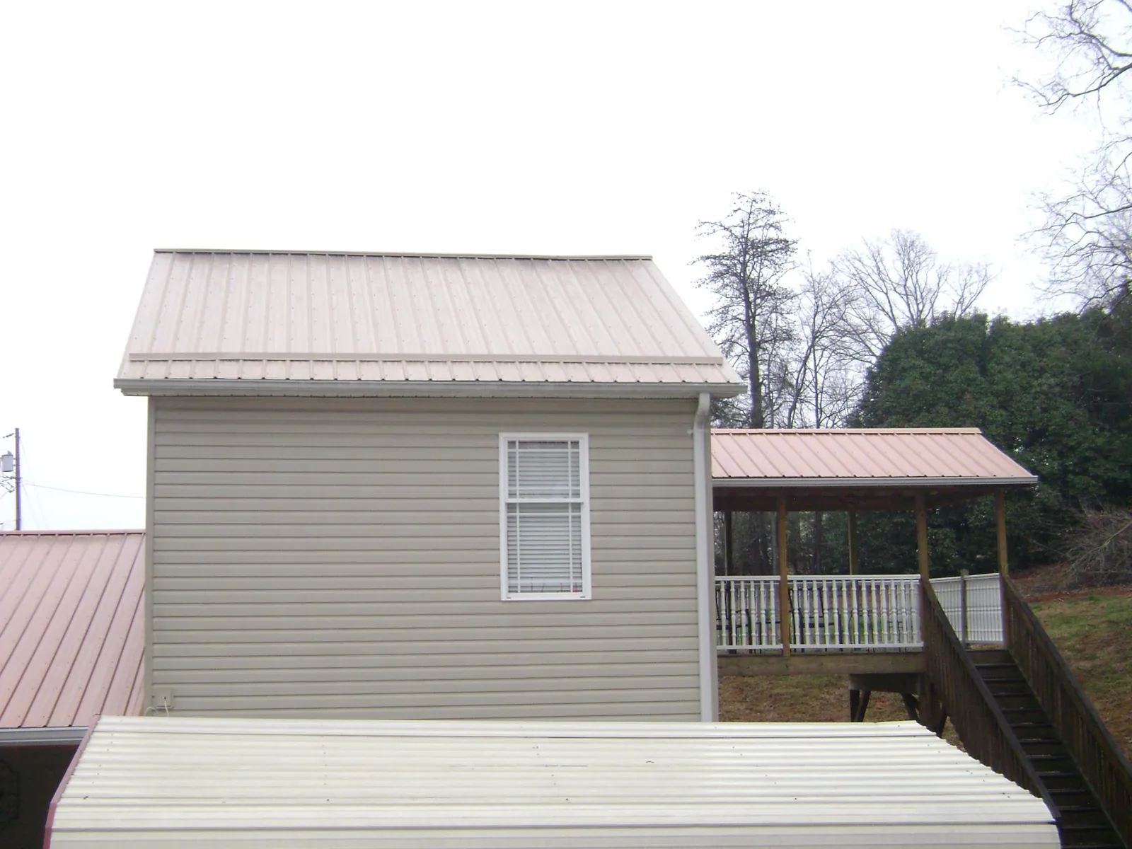 Tan metal roofs on a two story addition and attached porch, from a Roof Replacement job in Nathrop