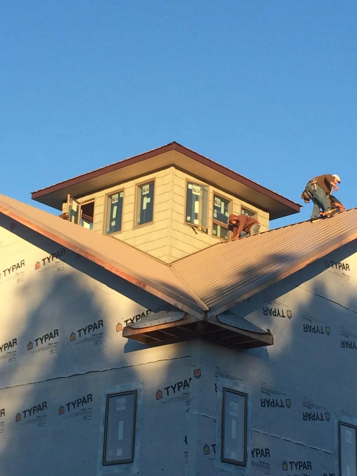 Roofers working around a rooftop cupola on a new metal roof at sunset — Roof Waterproofing in Nathrop by Roofing Brothers